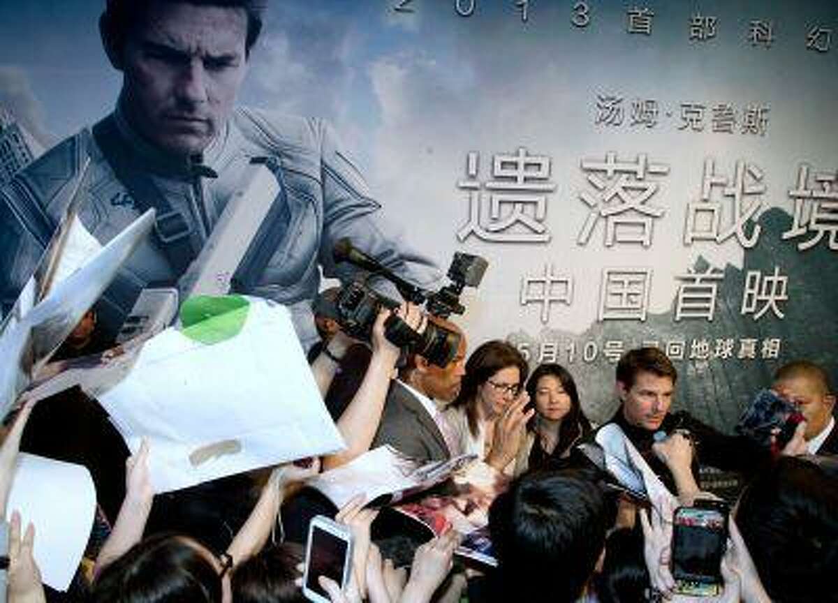 Actor Tom Cruise, right, signs autographs for his fans at the China premiere of his new movie "Oblivion" at a cinema in Beijing Thursday, May 9, 2013.