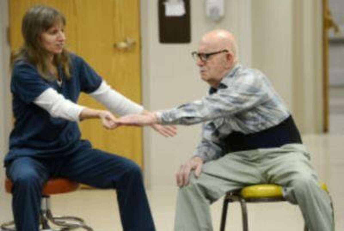 Janice Seabrooks, left, helps Tony Greco of West Manchester Township stretch during an exercise class for people who have Parkinson's disease at HealthSouth. Jennifer Harlacher, a senior therapist there, said fear of falling, embarrassment and depression sometimes prevent people from staying active after they've been diagnosed. (DAILY RECORD/SUNDAY NEWS - KATE PENN)