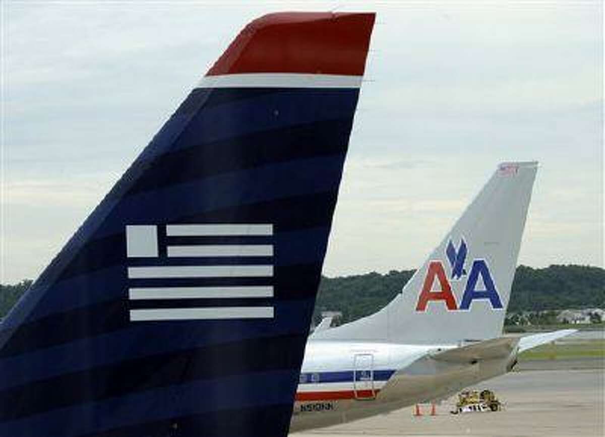 A US Airways, foreground, and an American Airlines plane are seen parked at the terminal at Washington's Ronald Reagan National Airport, Tuesday, Aug. 13, 2013. The Justice Department and a number of U.S. state attorneys general on Tuesday challenged a proposed $11 billion merger between US Airways Group Inc. and American Airlines' parent company, AMR Corp.(AP Photo/Susan Walsh)
