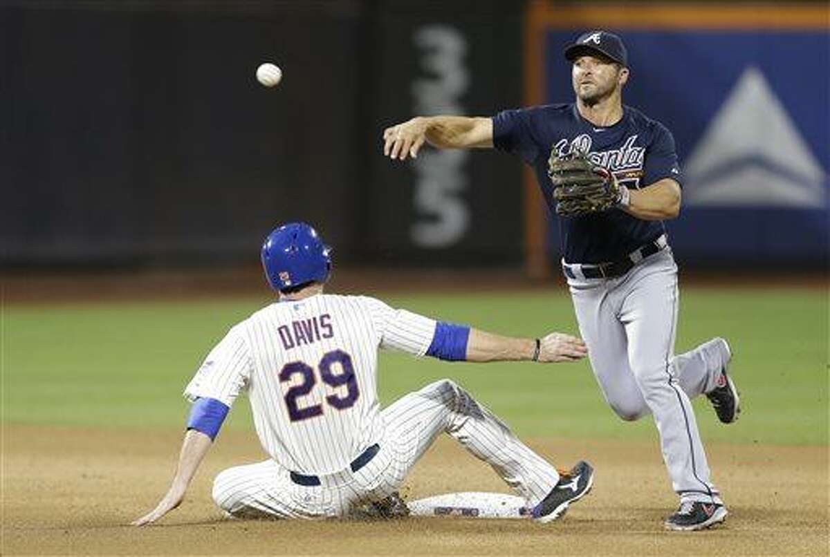 Atlanta Braves second baseman Dan Uggla (26) throws to first after forcing out New York Mets Ike Davis (29) after the Mets John Buck hit into a fourth-inning double play in a baseball game, Monday, July 22, 2013, in New York. (AP Photo/Kathy Willens)