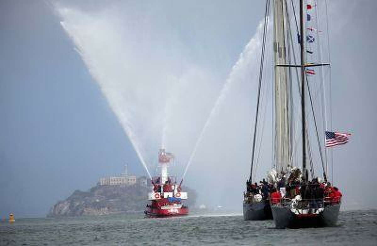 A San Francisco Fire Department boat leads the way, followed by a schooner and an America's Cup boat from 1976, as they past Alcatraz Island during the America's Cup Parade of Boats in San Francisco, Calif., on Friday, July 5, 2013.