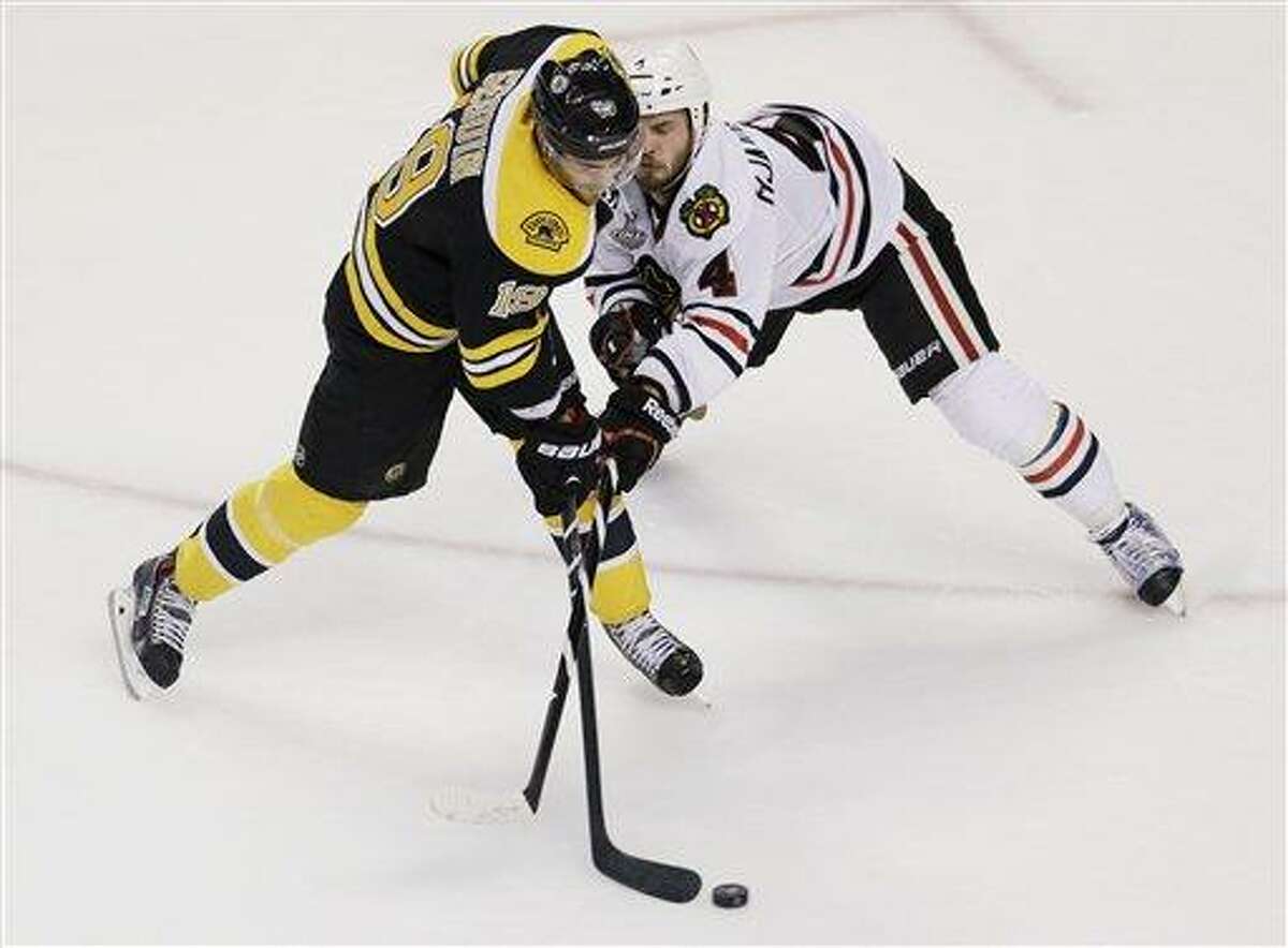Chicago Blackhawks defenseman Niklas Hjalmarsson (4), of Sweden, checks Boston Bruins center Tyler Seguin (19) during the first period in Game 4 of the NHL hockey Stanley Cup Finals, Wednesday, June 19, 2013, in Boston. (AP Photo/Charles Krupa)