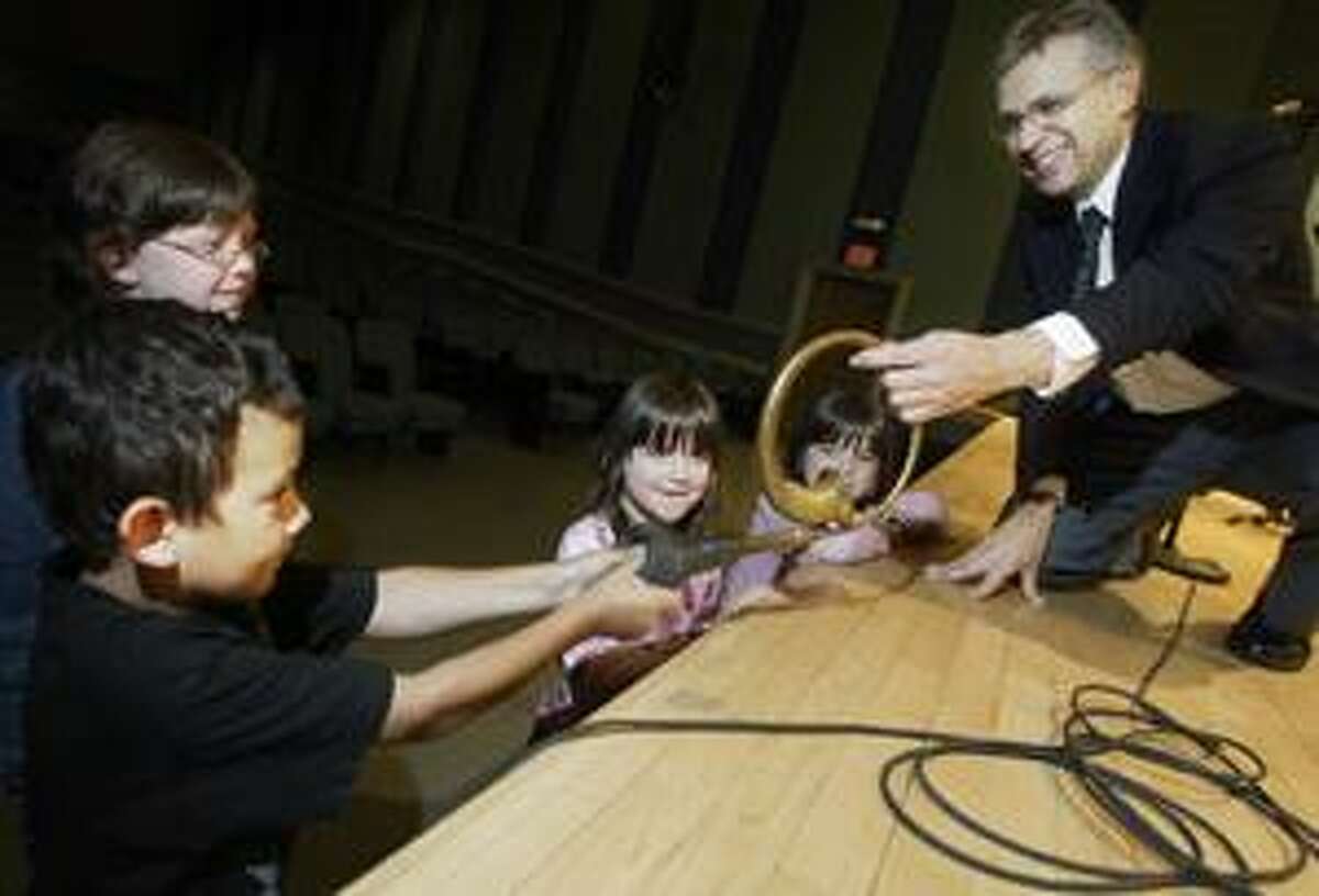 Dispatch Staff Photo by JOHN HAEGER Syracuse Symphony Percussion Ensemble member Ernie Muzquiz holds a klaxon horn as Nick Shrader, 7, squeezes it while Erin Garrison, 10, Claire Garrison, 6, and Anna Garrison, 6, look on before the start of the concert at Oneida High School on Friday, July 20, 2007.