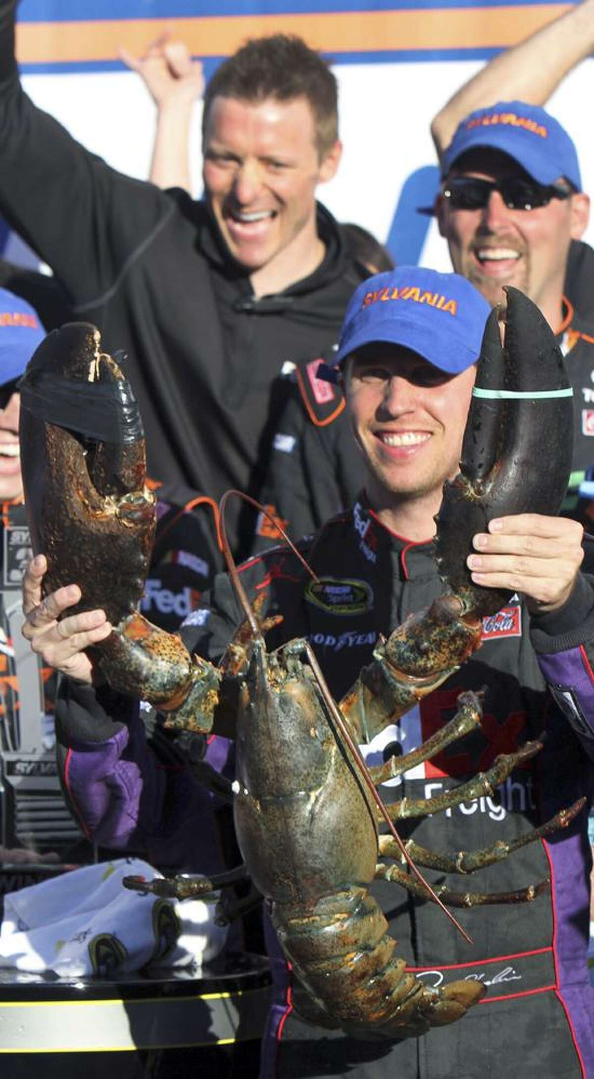 Denny Hamlin holds up a lobster in victory lane after winning the NASCAR Sprint Cup Series auto race at New Hampshire Motor Speedway, Sunday, Sept. 23, 2012, in Loudon, N.H. (AP Photo/Jim Cole)