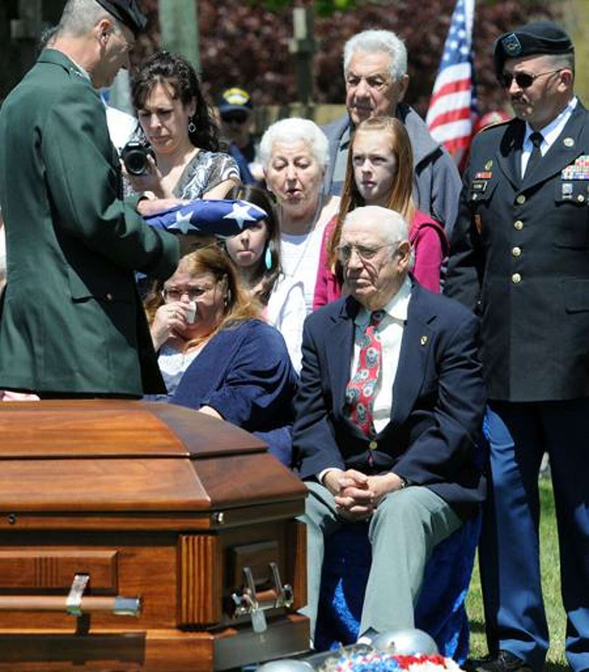 Korean War veteran Primo Carnabuci, who was missing in action and whose remains just recently were repatriated, is laid to rest Thursday at St. Mary's Cemetery in Clinton following a funeral in Old Saybrook. His brother, Dominic Carbanuci, right, and daughter, Ruth, second from right, receive an American flag from Army National Guard Brig. Gen. Steven Scorzato. Mara Lavitt/Register