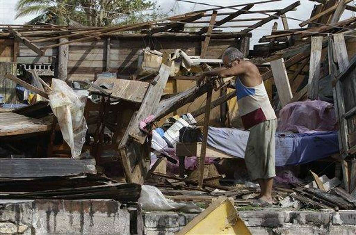 Resident Antonio Garces tries to recover his belongings from his house destroyed by Hurricane Sandy Thursday in Aguacate, Cuba. Associated Press