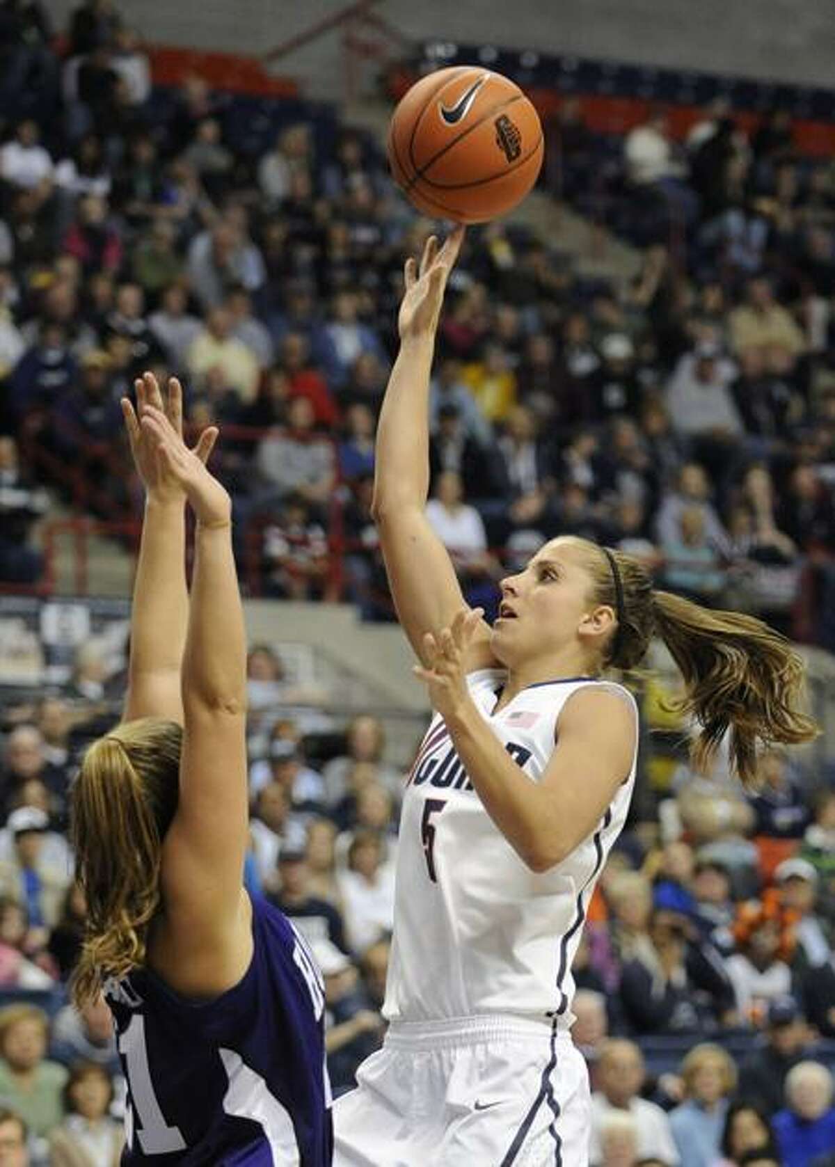 Connecticut's Caroline Doty, right, shoots over Holy Cross' Meredith Ward, left, in the second half of an NCAA women's college basketball game in Storrs, Conn., Sunday, Nov. 13, 2011. Doty, who sat out last season with her third major knee injury, scored nine points and played 22 minutes in her first game back since the 2010 national championship game. (AP Photo/Jessica Hill)