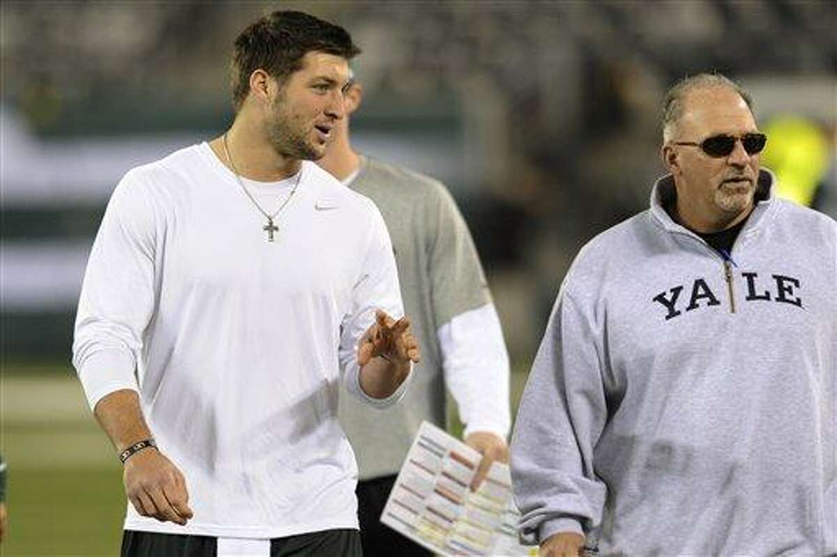 New York Jets quarterback Tim Tebow, center, walks the field with offensive coordinator Tony Sparano before an NFL football game against the New England Patriots Thursday, Nov. 22, 2012 in East Rutherford, N.J. (AP Photo/Bill Kostroun)