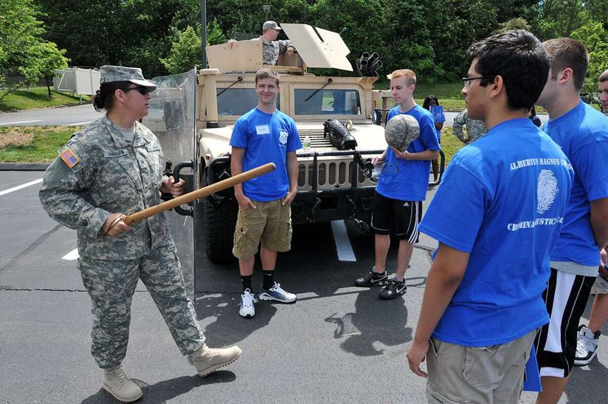 Staff Sgt. Candace Barquin of the Army National Guard 643rd MP unit explains riot control techniques to youths at the Criminal Justice Camp held at Albertus Magnus College. Peter Casolino/New Haven Register