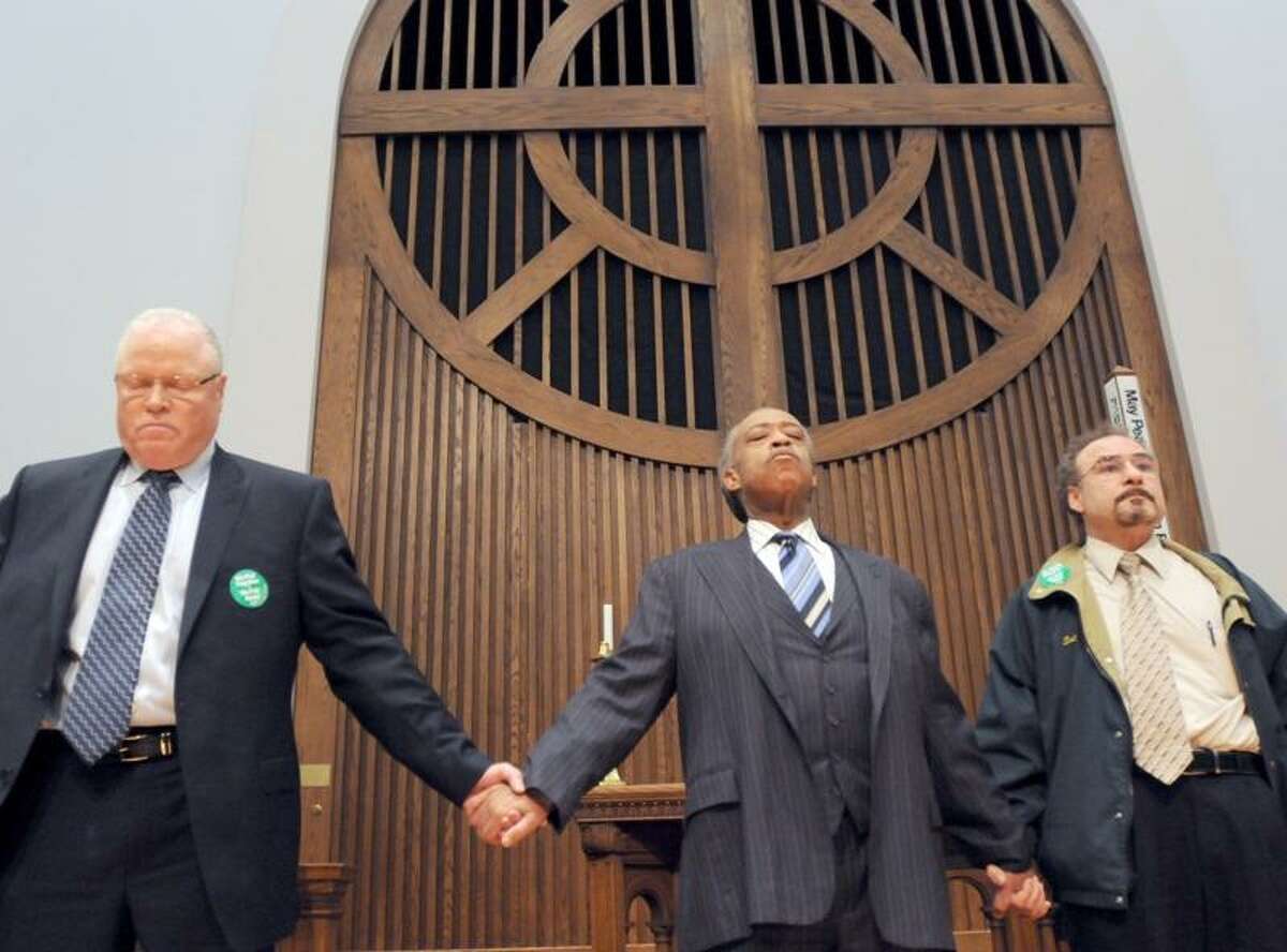 Rev. Al Sharpton of the National Action Network, center, flanked by Lee Saunders, Secretary-Treasurer of the AFSCME AFL-CIO, left, and Sal Luciano, Executive Director of Council 4 AFSCME, right, holds hands as they pray after a rally in support of City of New Haven workers and against anti-union sentiments of municipal and state government officials nationwide during a union rally Monday 3/14/11at the United Methodist Church in New Haven supporting City of New Haven unions. Photo by Peter Hvizdak / New Haven Register