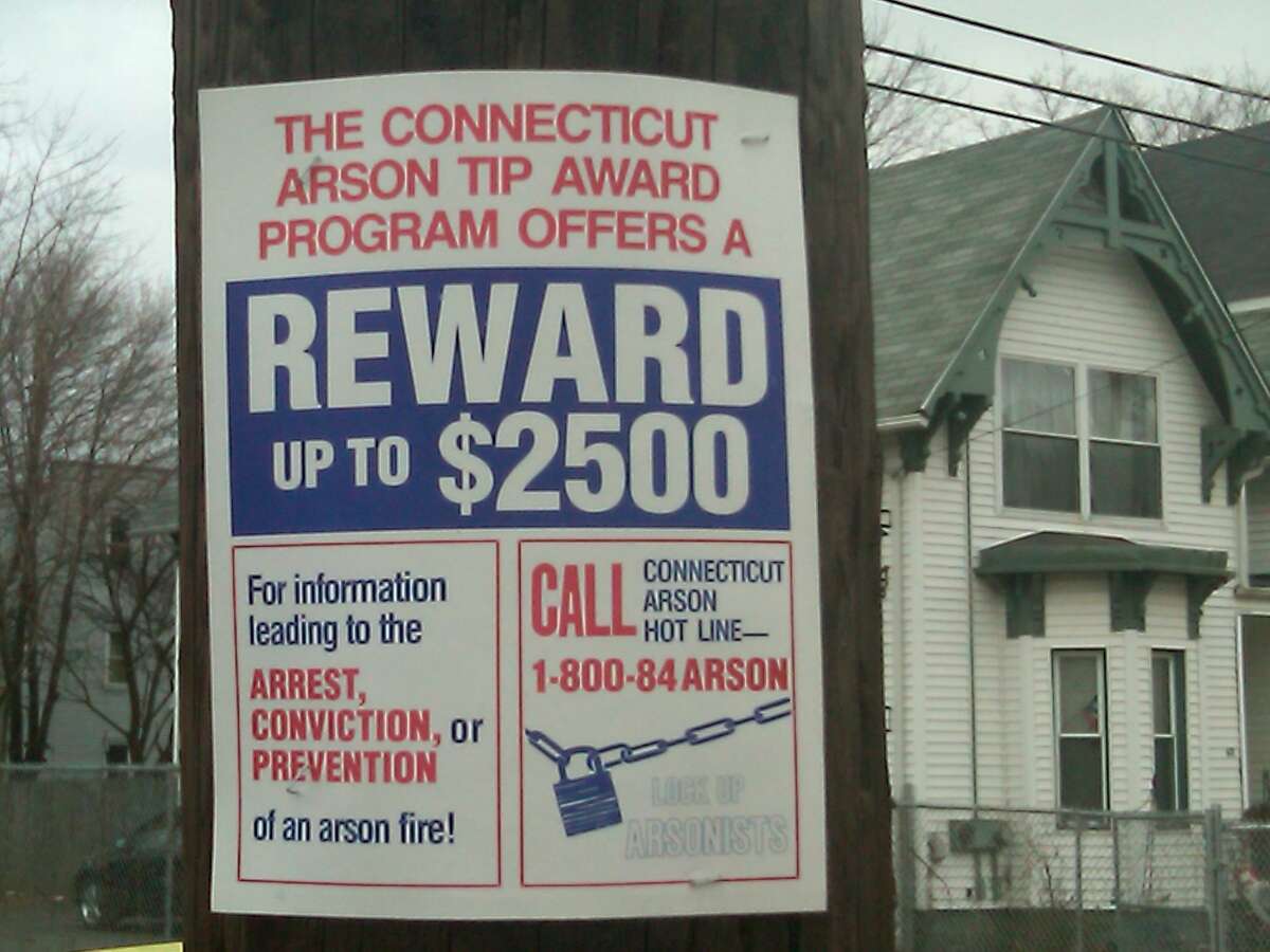 Signs such as this one offering a reward have gone up in the neighborhood where three New Haven residents died in an arson fire. Photo by William Kaempffer