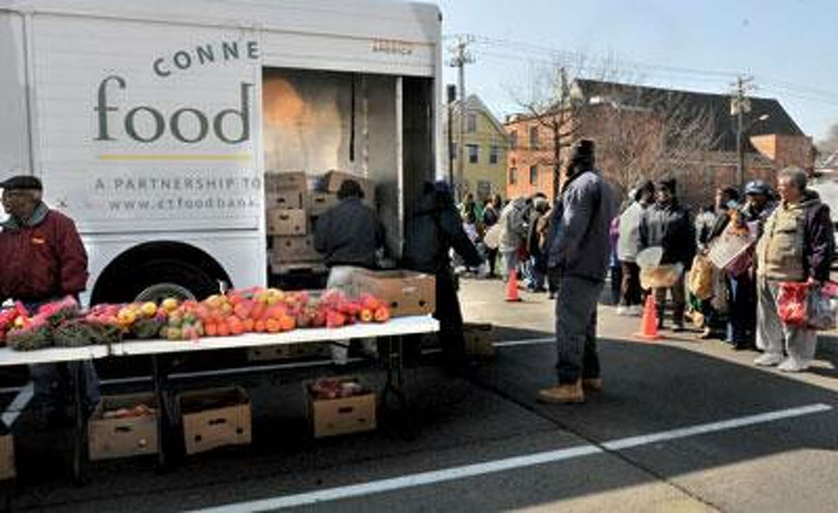 People stand in line to receive food from the Connecticut Mobile Food Bank. The truck is making it's monthly stop at the Community Baptist Church parking lot in New Haven. (Melanie Stengel/Register)