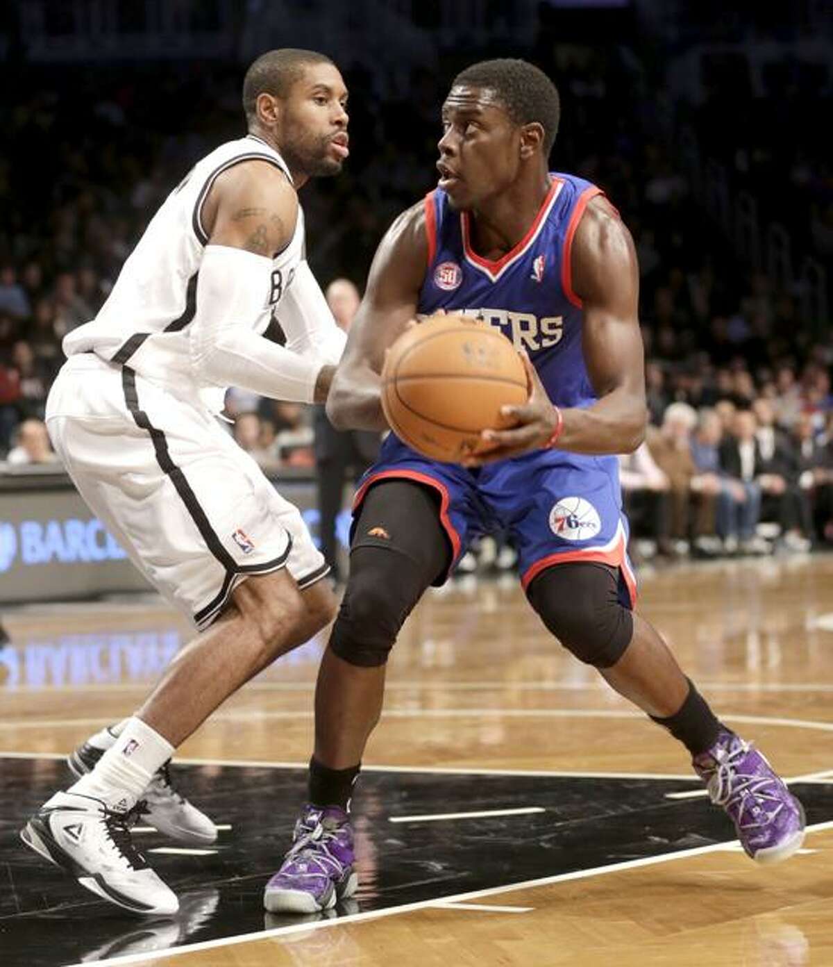 Philadelphia 76ers' Jrue Holiday, right, looks to the basket while Brooklyn Nets' C.J. Watson defends during the second half of an NBA basketball game at the Barclays Center Sunday, Dec. 23, 2012 in New York. The Nets beat the 76ers 95-92. (AP Photo/Seth Wenig)
