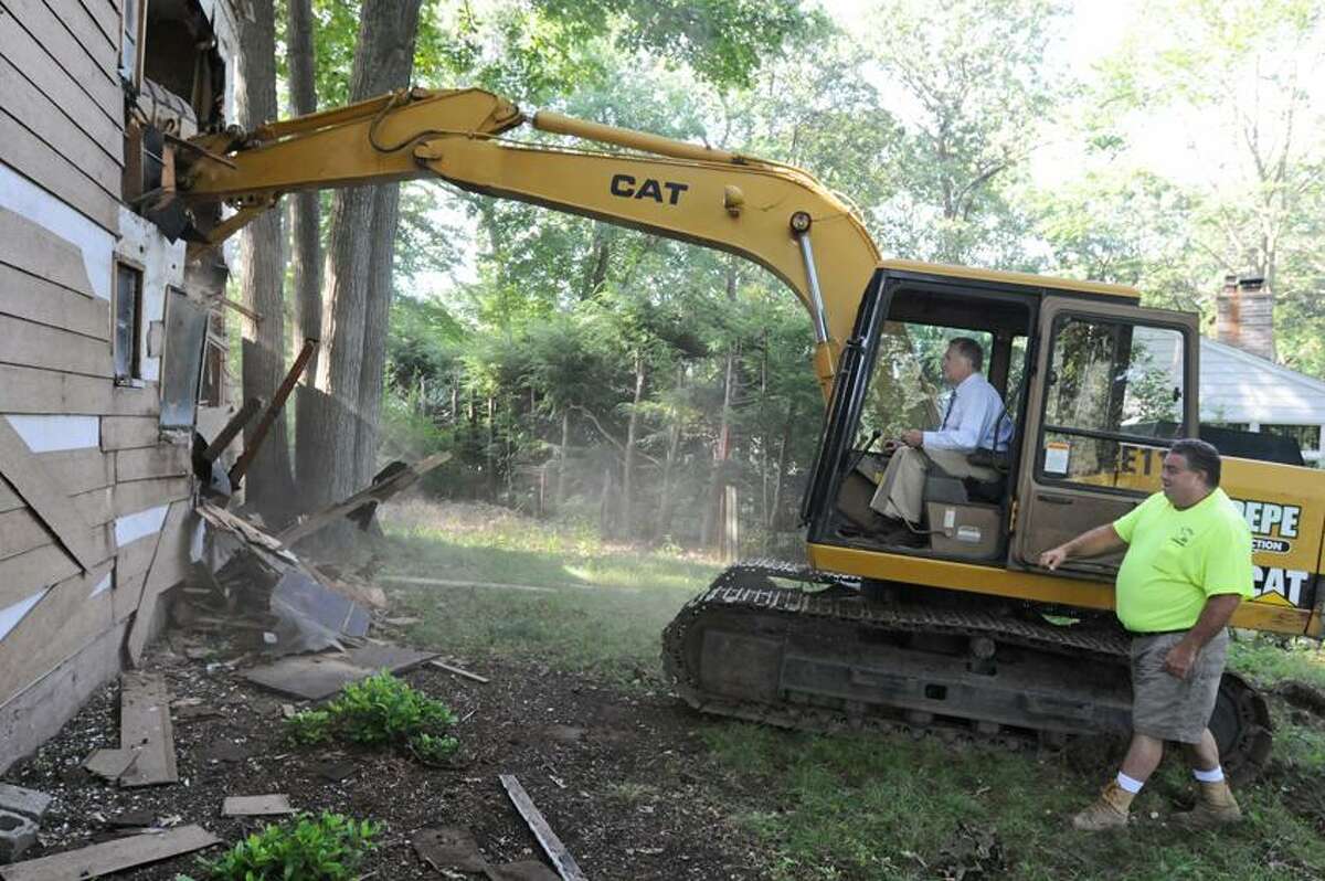 Frank Pepe, of Ansonia and owner of Pepe construction, supervises Ansonia Mayor James Della Volpe as Della Volpe begins the demolition with an excavator of a home in foreclosure Tuesday August 7, 2012 at 21 High Acres Road in Ansonia. A new home is being built there by Pepe and his partner Joe Moscato of Shelton which is part of a cleanup in the neighborhood. Photo by Peter Hvizdak / New Haven Register