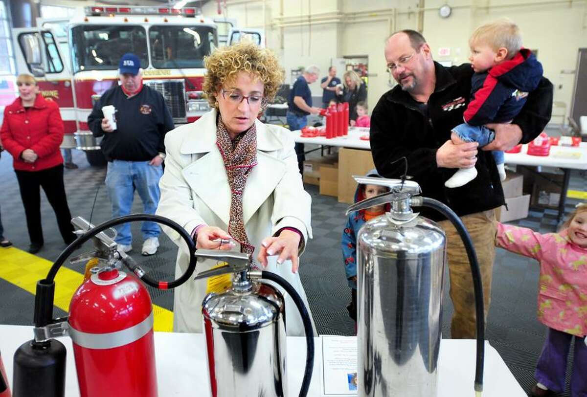 Barbara Block, center, of Woodbridge shows Bob Parker and his children how to use a fire extinguisher during a fire safety and education day at the Woodbridge Fire Department. Block's daughter, Eva, died in a house fire while away at Marist College earlier in the year. Arnold Gold/Register