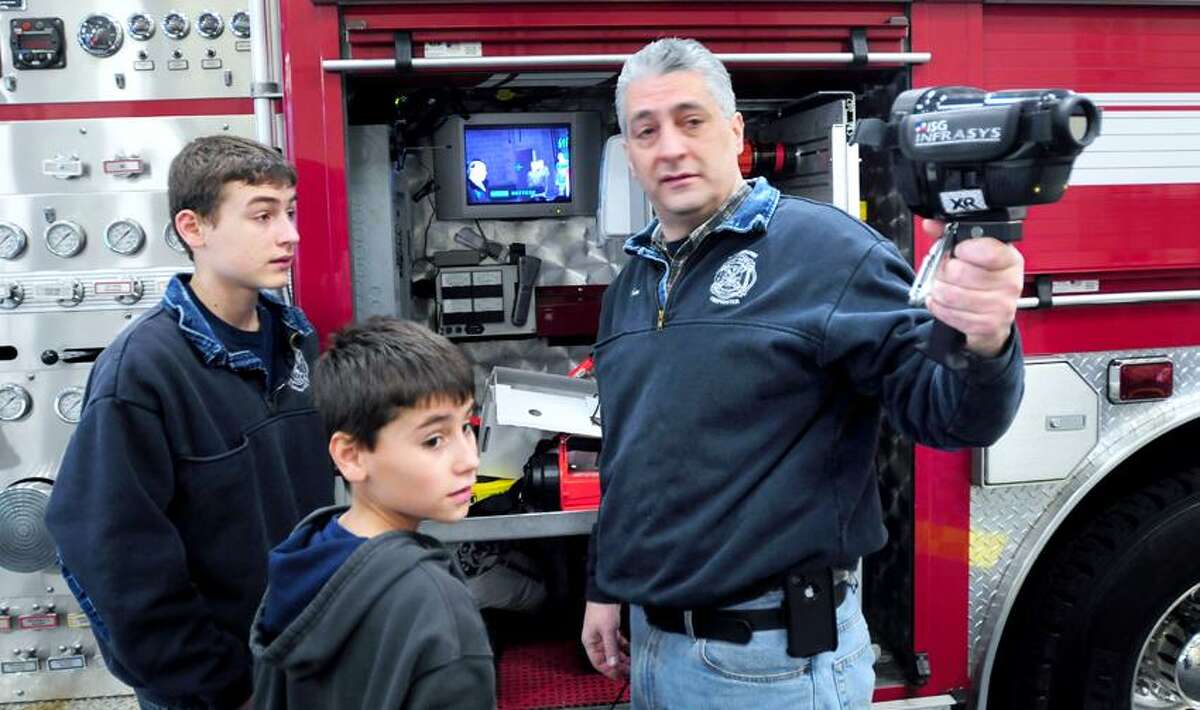 Volunteer firefighter Jim Kaoud, right, of Woodbridge shows his sons, R.J., left, 14, and Joey, center, 10, how an infrared camera works during a fire safety and education day at the Woodbridge Fire Department. Arnold Gold/Register