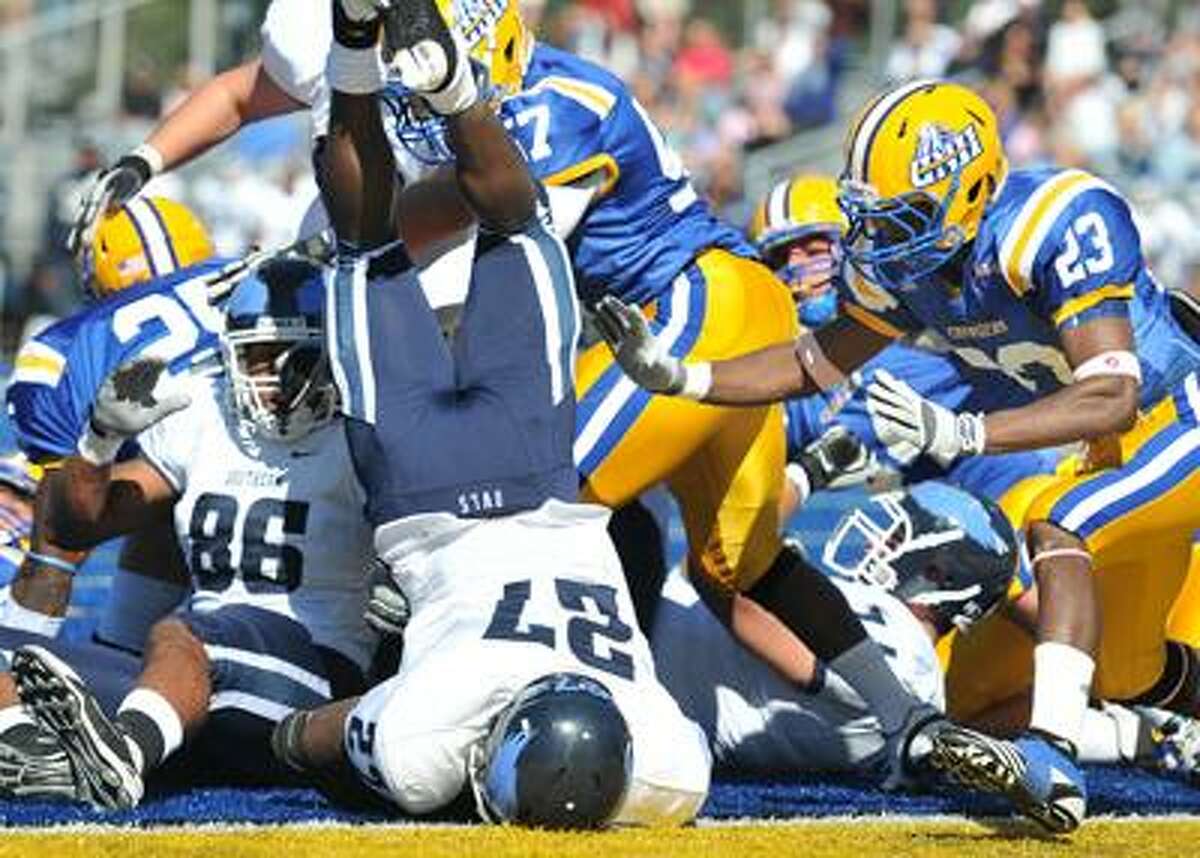 In an unbelievable stand just inches from the goal line, the New Haven defense stops SCSU running back Rashad Slowley (27) as he comes down over the top of the pile. UNH held SCSU on the next play as well. At right is UNH's Bernard Risco. (Peter Casolino/Register)