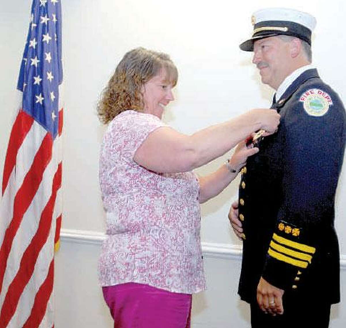 Peter Hvizdak/Register Cindy Fitzmaurice pins a badge on her husband, William Fitzmaurice, as he is promoted to battalion chief of the Hamden Fire Department during a swearing-in ceremony recently at the Hamden Government Center.