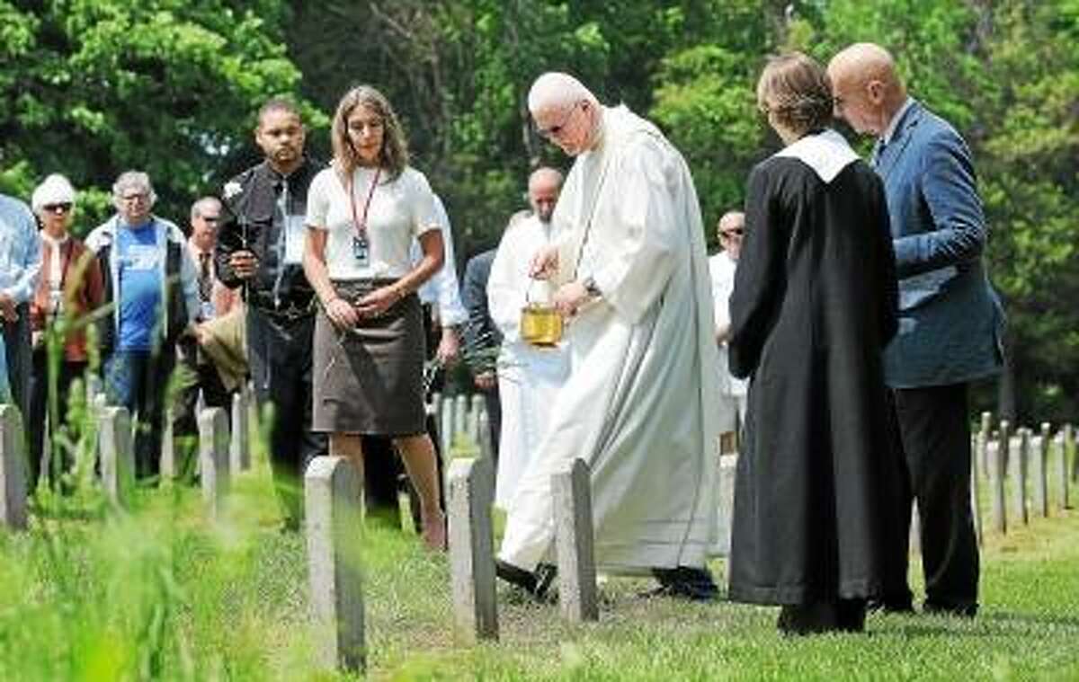 Catherine Avalone/The Middletown Press Deacon Peter Gill of St. Coleman Parish in Middlefield blesses a gravesite of a patient during the fifteenth year of the continuing ceremony recognizing people buried in the Connecticut Valley Hospital cemetery on Silvermine Road between 1878 and 1955.