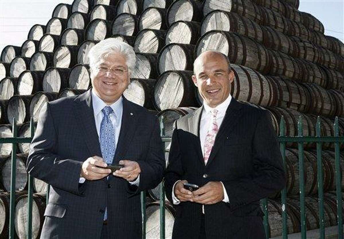 In this July 14, 2009 file photo, BlackBerry maker Research in Motion's co-CEOs Jim Balsillie and Mike Lazaridis pose with their Blackberry devices before the RIM annual general meeting in Waterloo, Ontario. The company on Sunday says Balsillie and Lazaridis are stepping down, and will be replaced by Thorsten Heins, a chief operating officer who joined RIM four years ago from Siemens AG. Associated Press