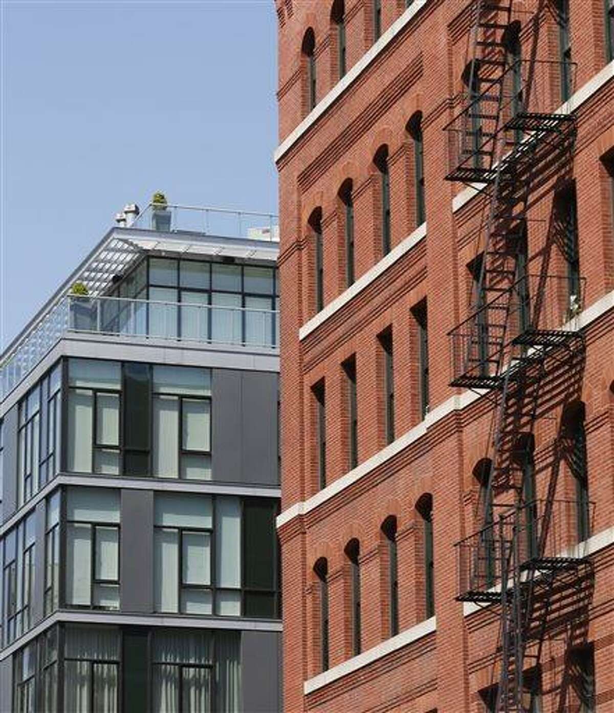 A modern luxury glass apartment building, left, sits across the street from an older red brick apartment, the home of photograher Arne Svenson, Thursday, May 16, 2013 in New York. Residents of a New York luxury apartment building are livid over an exhibition of photos secretly snapped through their apartment windows. (AP Photo/Bebeto Matthews)