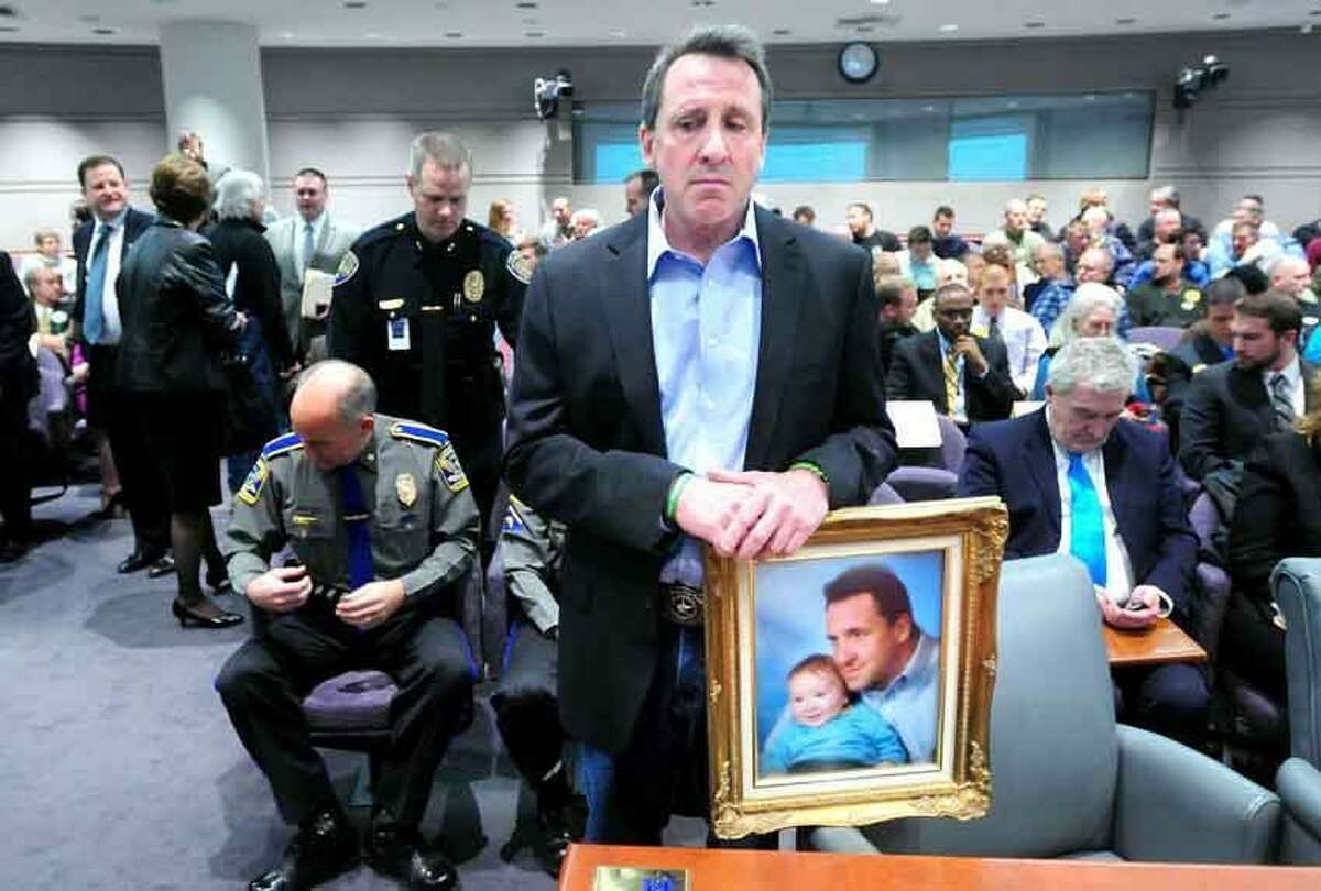 Neil Heslin of Shelton, holding a photograph of himself with his son Jesse Lewis, prepares to give testimony Jan. 28 at a legislative hearing about gun control at the Legislative Office Building in Hartford. His son was killed at the Sandy Hook shootings in December. New Haven Register file photo