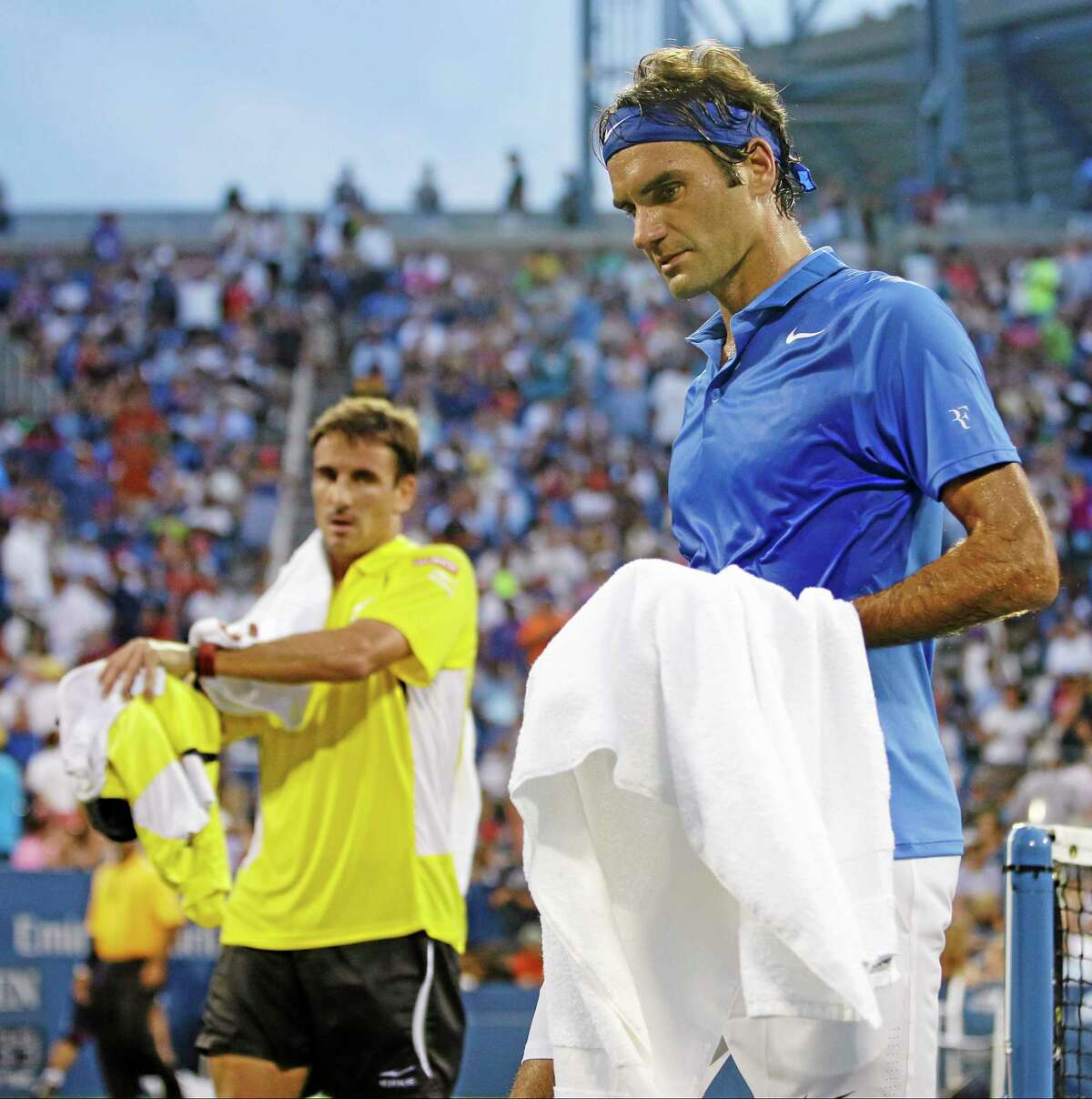 Roger Federer right, and Tommy Robredo walk off the court during a break in play during the fourth round of the U.S. Open Monday in New York.