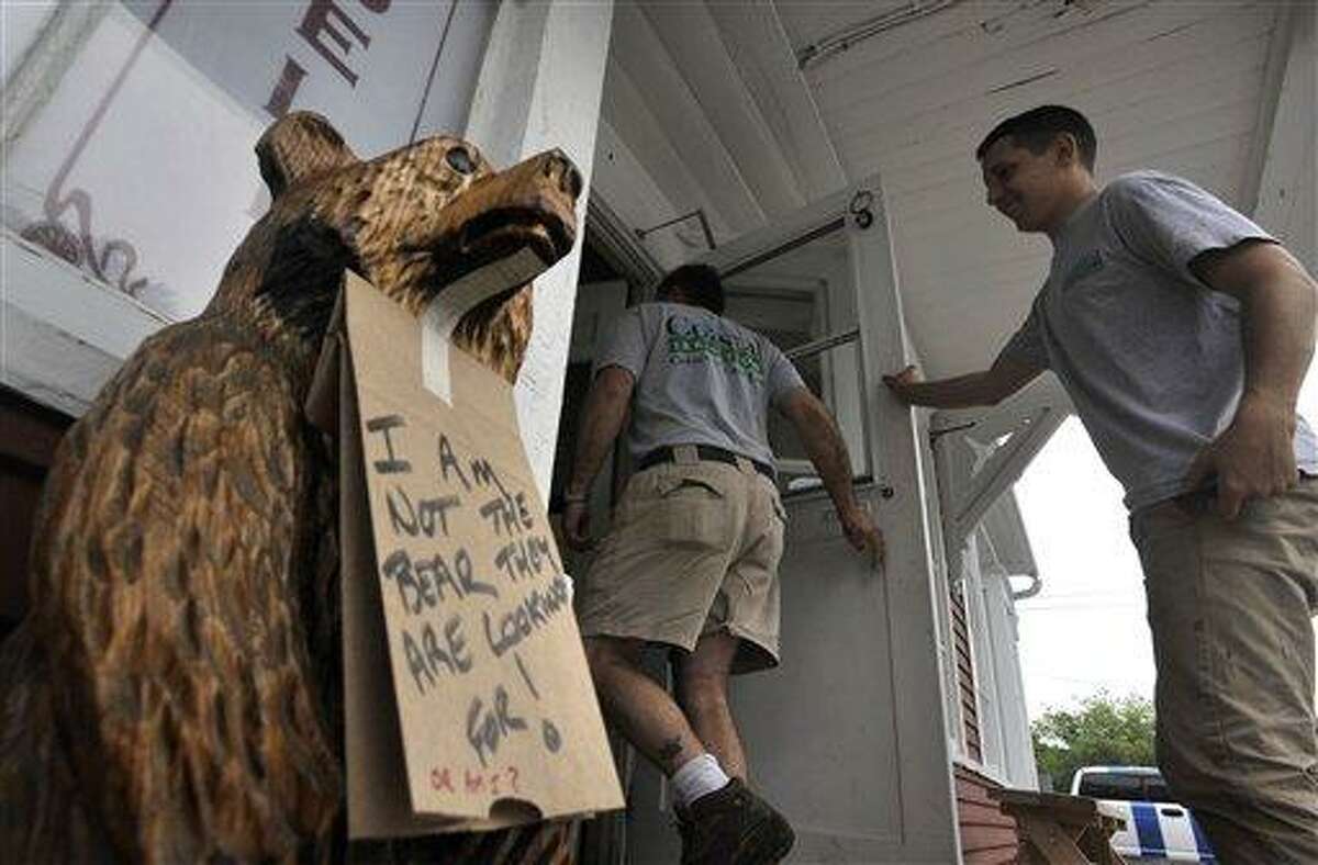 In this May 29 file photo, a sign hangs around the neck of a wooden bear at the entrance to the Old Village Store, in West Barnstable, Mass. A 200-pound black bear caught the imagination of Massachusetts residents as it meandered across Cape Cod before being relocated to central Massachusetts. Associated Press