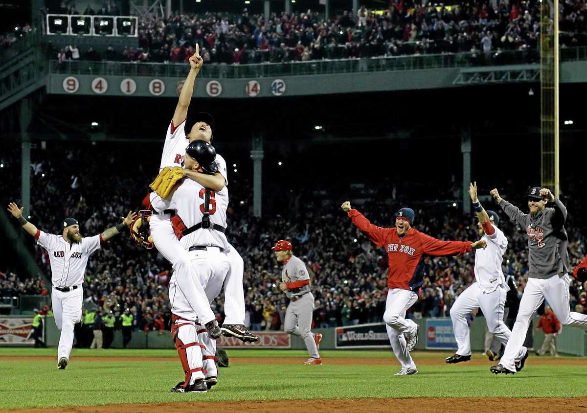 Red Sox relief pitcher Koji Uehara and catcher David Ross celebrate after getting the St. Louis Cardinals’ Matt Carpenter to strike out and end Game 6 of the World Series Wednesday in Boston. The Red Sox won 6-1 to win the Series.