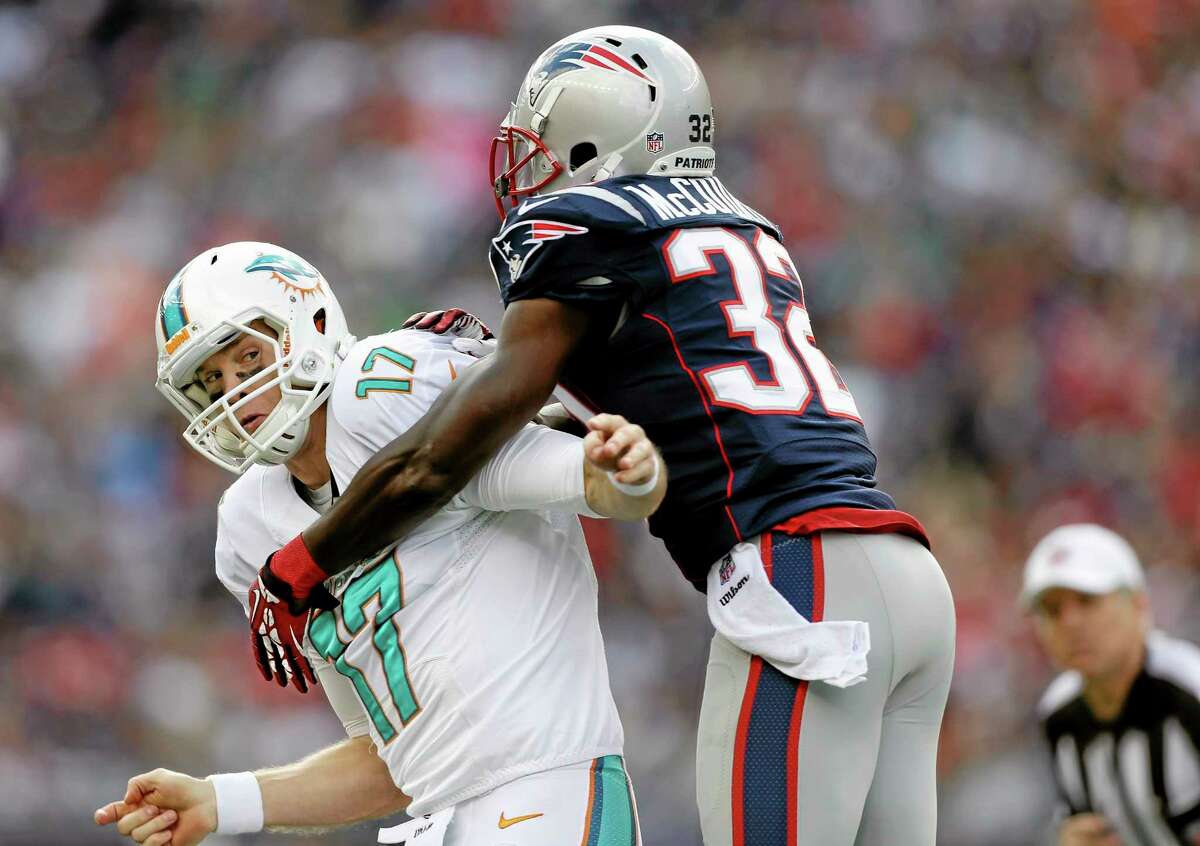 New England Patriots free safety Devin McCourty (32) grabs Miami Dolphins quarterback Ryan Tannehill during the first quarter of Sunday’s game in Foxborough, Mass.