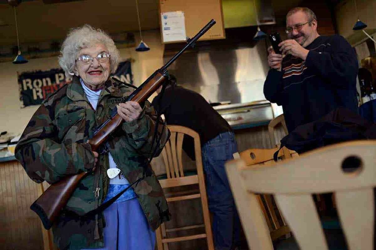Lee Lazernick, right, asked his mother Thelma Lazernick, left, to pose with a customer's Ruger Mini-14 .223 semi-automatic rifle on Monday, Feb. 18, 2013, at All Around Pizza and Deli in Virginia Beach, Va., where customers wearing weapons or who bring their concealed weapons permit are offered a 15 percent discount. (AP Photo/The Virginian-Pilot, Amanda Lucier)
