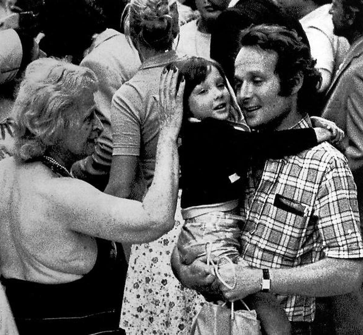 A father holds his daughter in his arms while a relative pats her head after the girl was flown to Orly Airport in Paris from Entebbe, Uganda, June 30, 1976. She was among 46 hostages released by Palestinian hijackers and flown to Paris in an Air France plane. (AP Photo)