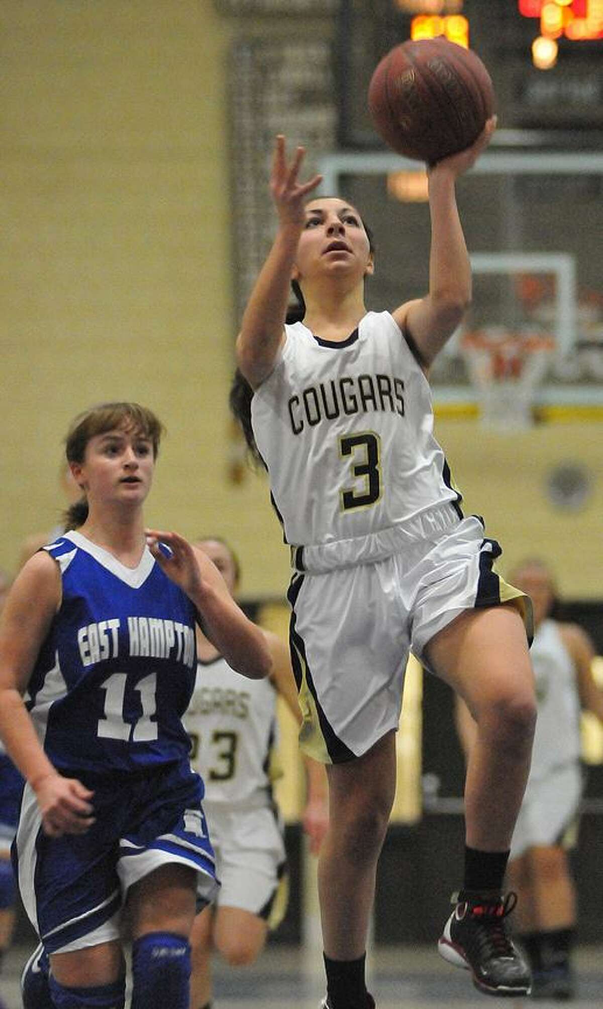 Catherine Avalone/The Middletown PressHaddam-Killingworth junior guard Maya Savino drives past East Hampton freshman point guard Renee Radavich and goes for two Monday night in Higganum. The H-K Cougars defeated the East Hampton Bellringers 48-22 in the .