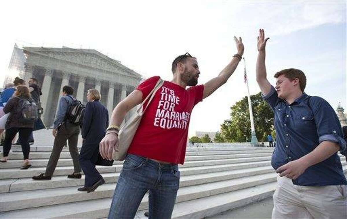 Gay rights activist Bryce Romero, who works for the Human Rights Campaign, offers an enthusiastic high-five to visitors getting in line to enter the Supreme Court on a day when justices are expected to hand down major rulings on two gay marriage cases that could impact same-sex couples across the country, in Washington, Wednesday, June 26, 2013. (AP Photo/J. Scott Applewhite)
