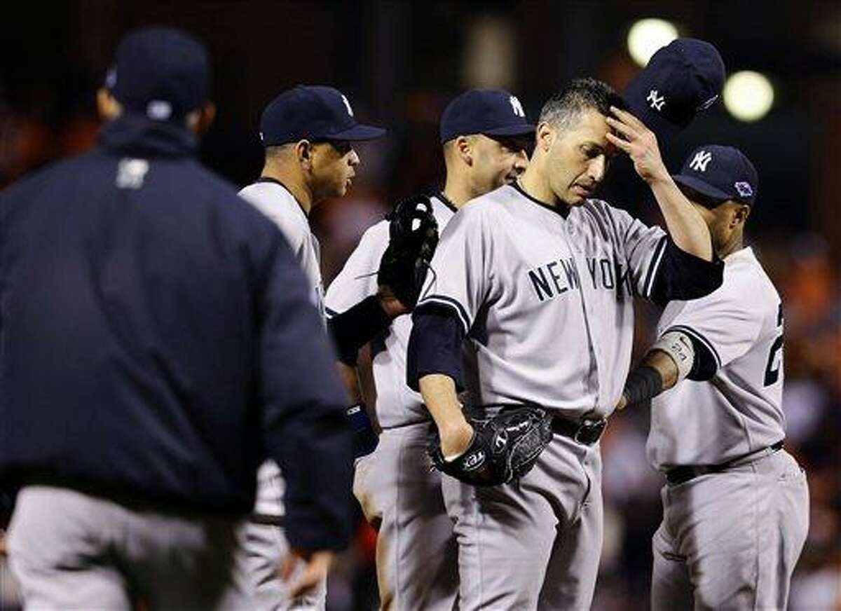 New York Yankees starting pitcher Andy Pettitte removes his cap as manager Joe Girardi, far left, walks out to relieve him in the eighth inning of Game 2 of the American League division baseball series against the Baltimore Orioles, Monday, Oct. 8, 2012, in Baltimore. Baltimore won 3-2. (AP Photo/Alex Brandon)