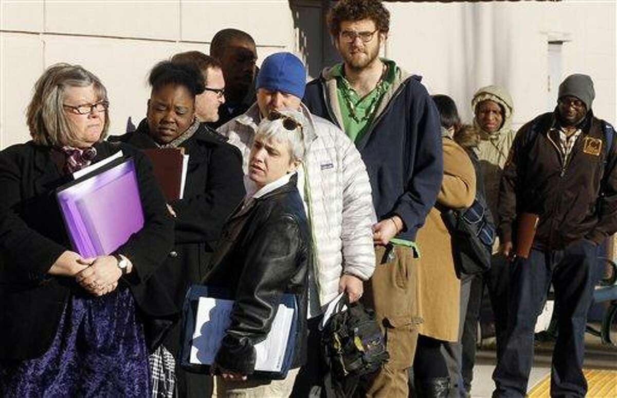 In this January file photo, people wait in line to enter a job fair/employer hiring event for Safeway, in Portland, Ore. The number of people seeking unemployment aid declined to nearly a four-year low last week, a hopeful sign that the job market's steady gains in recent months will continue. Associated Press