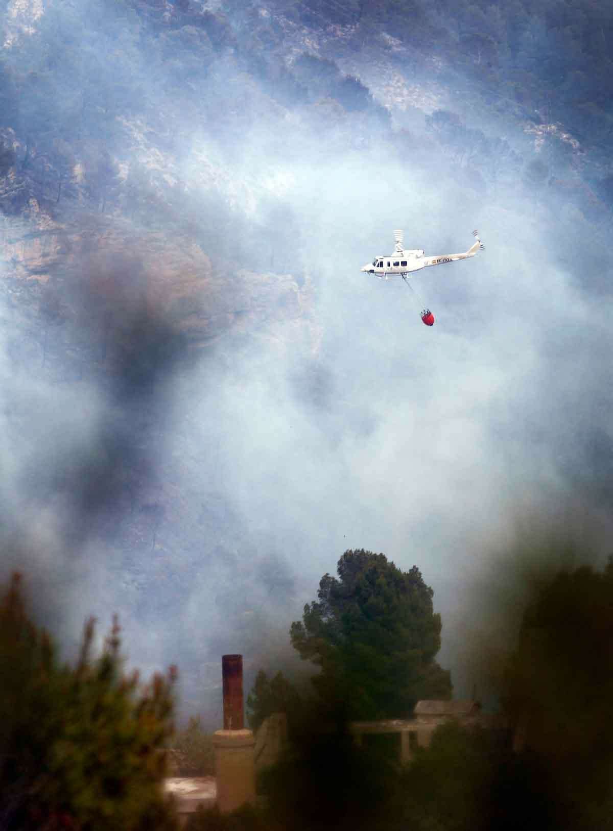 A helicopter flies next over a wildfire in Tuejar, near Valencia, Spain, on Saturday, June 2, 2012. Regional government said wildfire has burned almost 1000 hectares (2400 acres) of forest, while more than 300 firefighters, 8 helicopters and 9 planes are working to stop the fire. (AP Photo/Alberto Saiz)