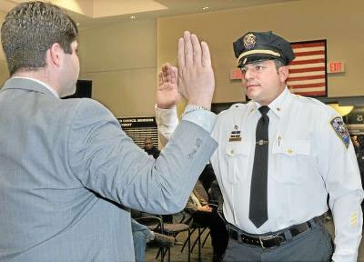 Catherine Avalone/The Middletown Press Mayor Dan Drew swears in Michael Timbro as the new Deputy Police Chief of Middletown Friday night at council chambers at city hall.