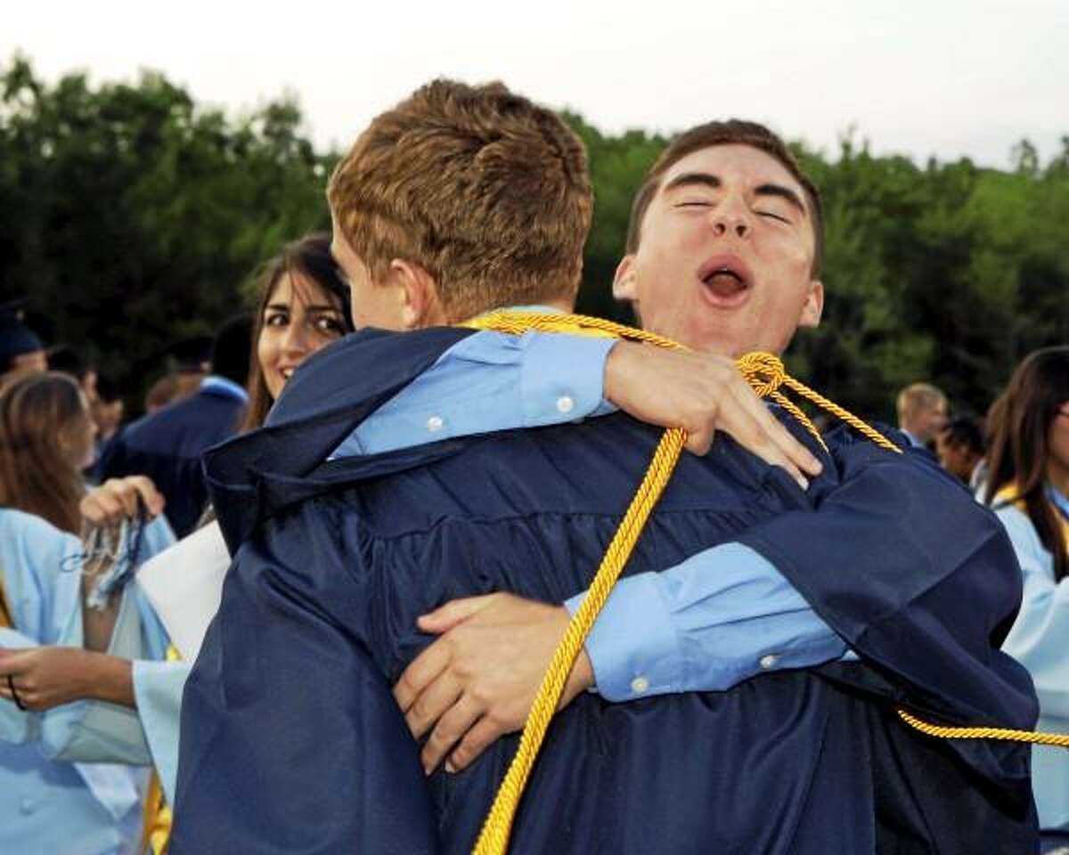 Sandy Aldieri/Special to the Press/Drew Cietek hugs friend, Chris Polson, while fellow classmate Fatima Bishtawi looks on as graduates celebrated after the Middletown High graduation ceremonies on Friday.