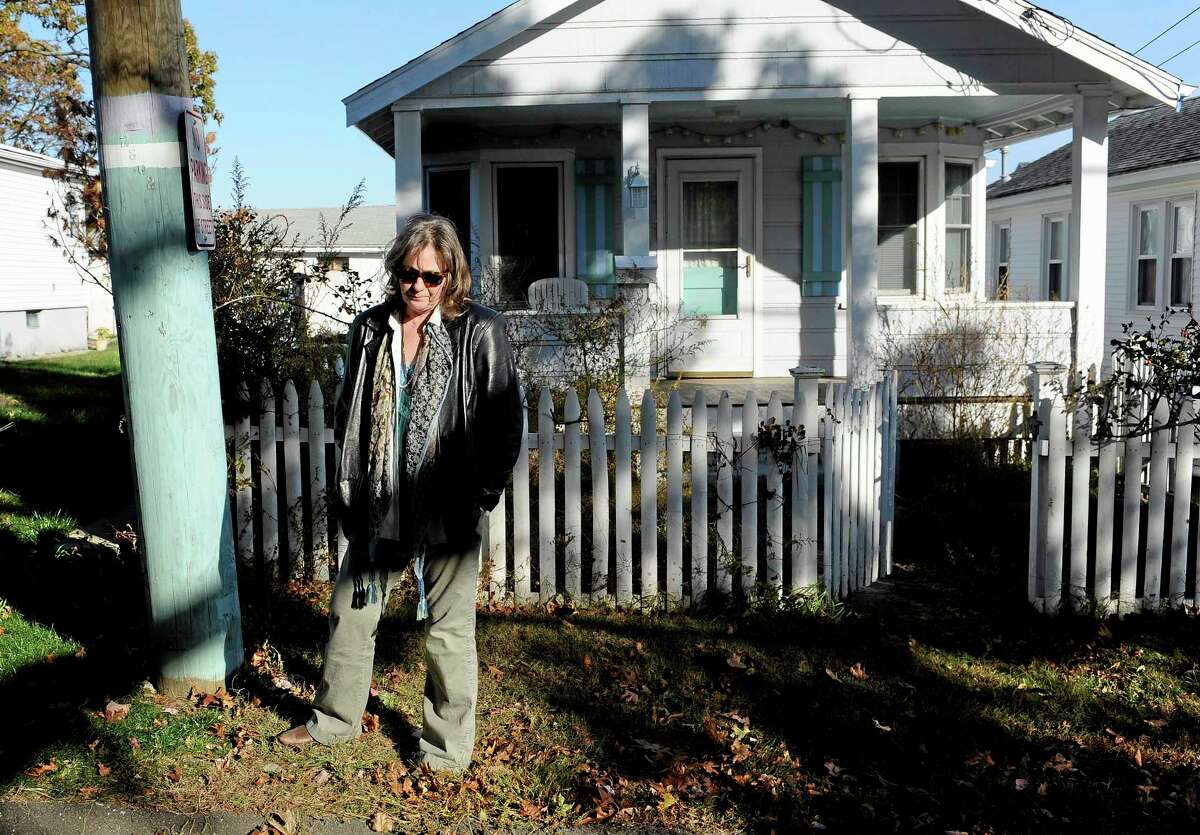Deborah Dinan stands next to a telephone pole she painted to match her home behind her, Monday, Oct. 28, 2013, in Milford, Conn. Dinan is among hundreds of Connecticut residents still out of their homes since Superstorm Sandy struck. In Milford alone, at least 200 families remain displaced, officials said. (AP Photo/Jessica Hill)