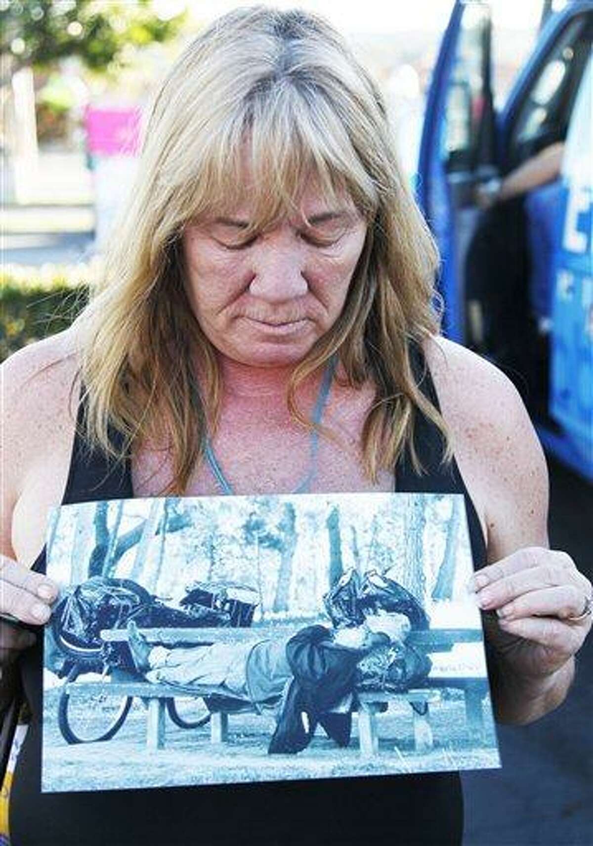 Anaheim, Calif., resident Marilyn Holland holds a photo of John Berry, 64, a Vietnam homeless veteran who was stabbed to death by a serial killer, as she pays her respects in Anaheim Wednesday. Prosecutors have charged Itzcoatl Ocampo, 23, a former Marine and a Iraq war veteran, with the murders of four homeless men in a near month-long spree that prompted police in Orange County to urge the homeless to seek shelter indoors. Associated Press