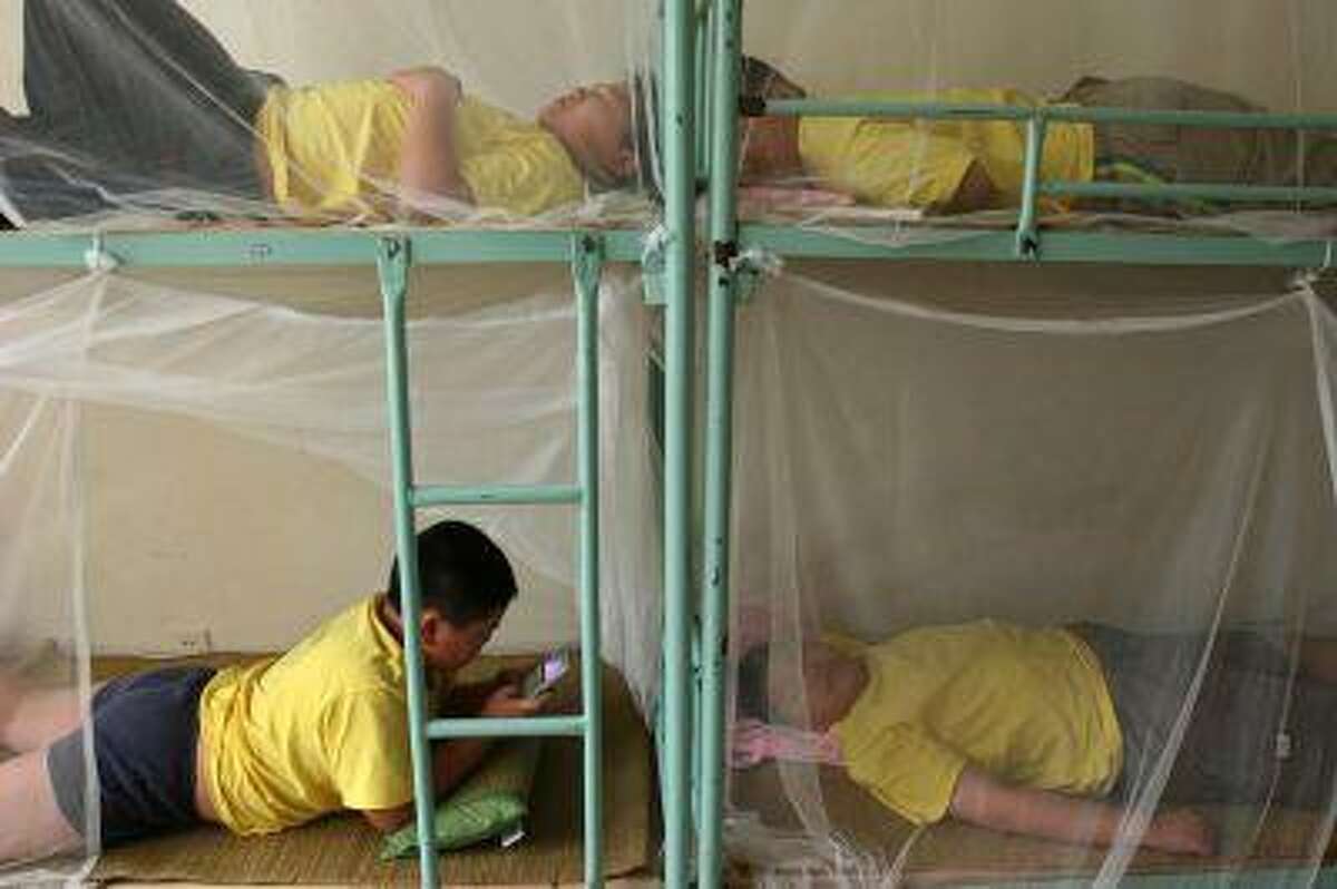 Children rest during a weight-losing summer camp organized by a slimming centre in Wuhan, central China's province July 13, 2006. CHINA OUT REUTERS/Stringer