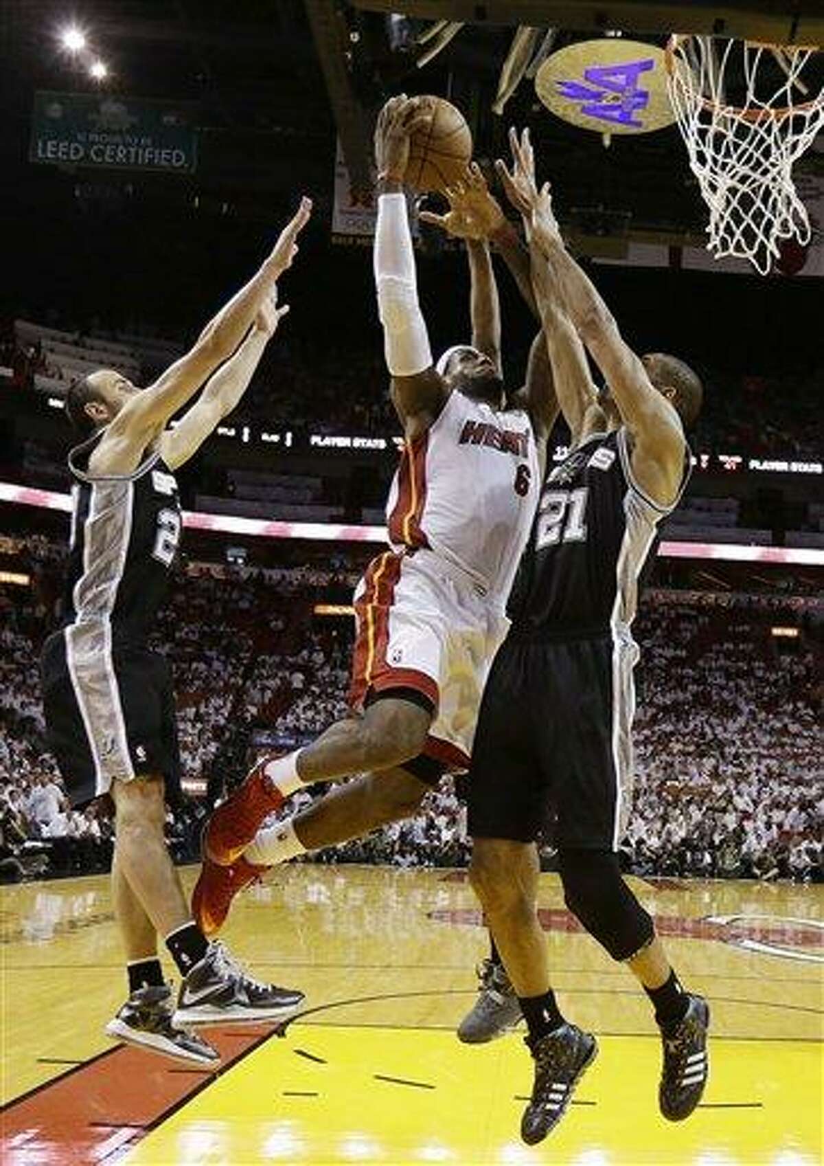 Miami Heat forward LeBron James (6) drives to the basket as San Antonio Spurs power forward Tim Duncan (21) and guard Manu Ginobili (20) of Argentina defend during the first half of Game 6 of the NBA Finals basketball game against the San Antonio Spurs, Tuesday, June 18, 2013 in Miami. The Heat defeated the Spurs 103-100 in overtime. (AP Photo/Lynne Sladky)