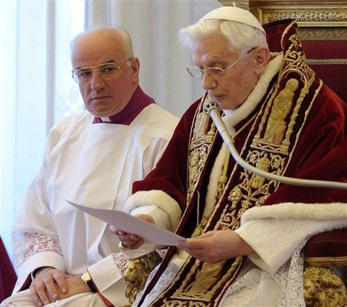 In this photo provided by the Vatican newspaper L'Osservatore Romano, Mons. Franco Comaldo, left, a pope aide, looks at Pope Benedict XVI as he reads a document in Latin where he announces his resignation, during a meeting of Vatican cardinals, at the Vatican, Monday, Feb. 11, 2013. Benedict XVI announced Monday that he would resign Feb. 28 - the first pontiff to do so in nearly 600 years. The decision sets the stage for a conclave to elect a new pope before the end of March. (AP Photo/L'Osservatore Romano, ho)
