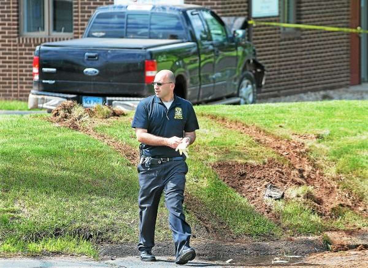 Catherine Avalone/The Middletown Press Connecticut State Police investigate the scene where a Cromwell man was shot and wounded by a Cromwell Police officer after crashing his Ford pickup truck into a medical building on the corner of West and Washington Street in Cromwell early Wednesday morning.