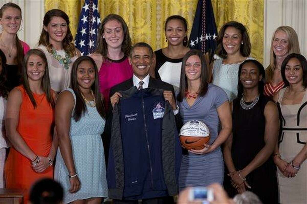 President Barack Obama poses with a jacket and an autographed ball during a ceremony in the East Room of the White House to honor the University of Connecticut Huskies for their 2013 NCAA Women's Basketball Championship win, Wednesday, July 31, 2013, in Washington. University of Connecticut Huskies seen from top left are, Heather Buck, Stefanie Dolson, Breanna Stewart, Kiah Stokes and assistant coaches Marisa Moseley and Shea Ralph, from bottom left, Caroline Doty, Kaleena Mosqueda-Lewis, Kelly Faris, Brianna Banks and Bria Hartley. (AP Photo/Carolyn Kaster)