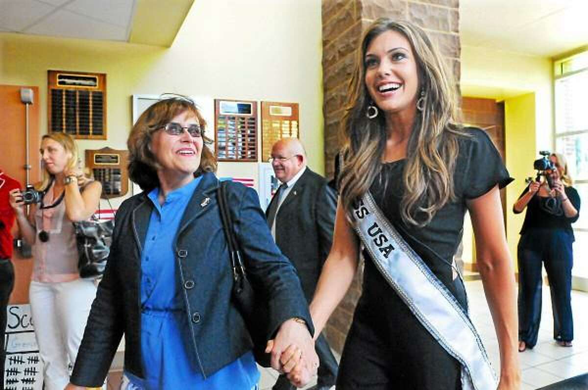 Portland First Selectwoman Susan Bransfield escorts Miss USA Erin Brady to the Portland High School cafeteria to visit with kids in the town's Day Camp Tuesday afternoon. Brady joined in singing camp songs, signed autographs and served hot fudge sundaes. (Catherine Avalone - The Middletown Press)