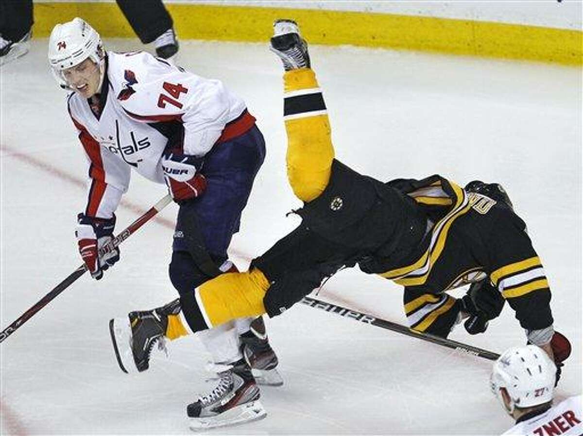 Washington Capitals defenseman John Carlson (74) upends Boston Bruins left wing Brad Marchand (63) during the third period of Game 1 of an NHL hockey Stanley Cup first-round playoff series in Boston, Thursday, April 12, 2012. (AP Photo/Charles Krupa)