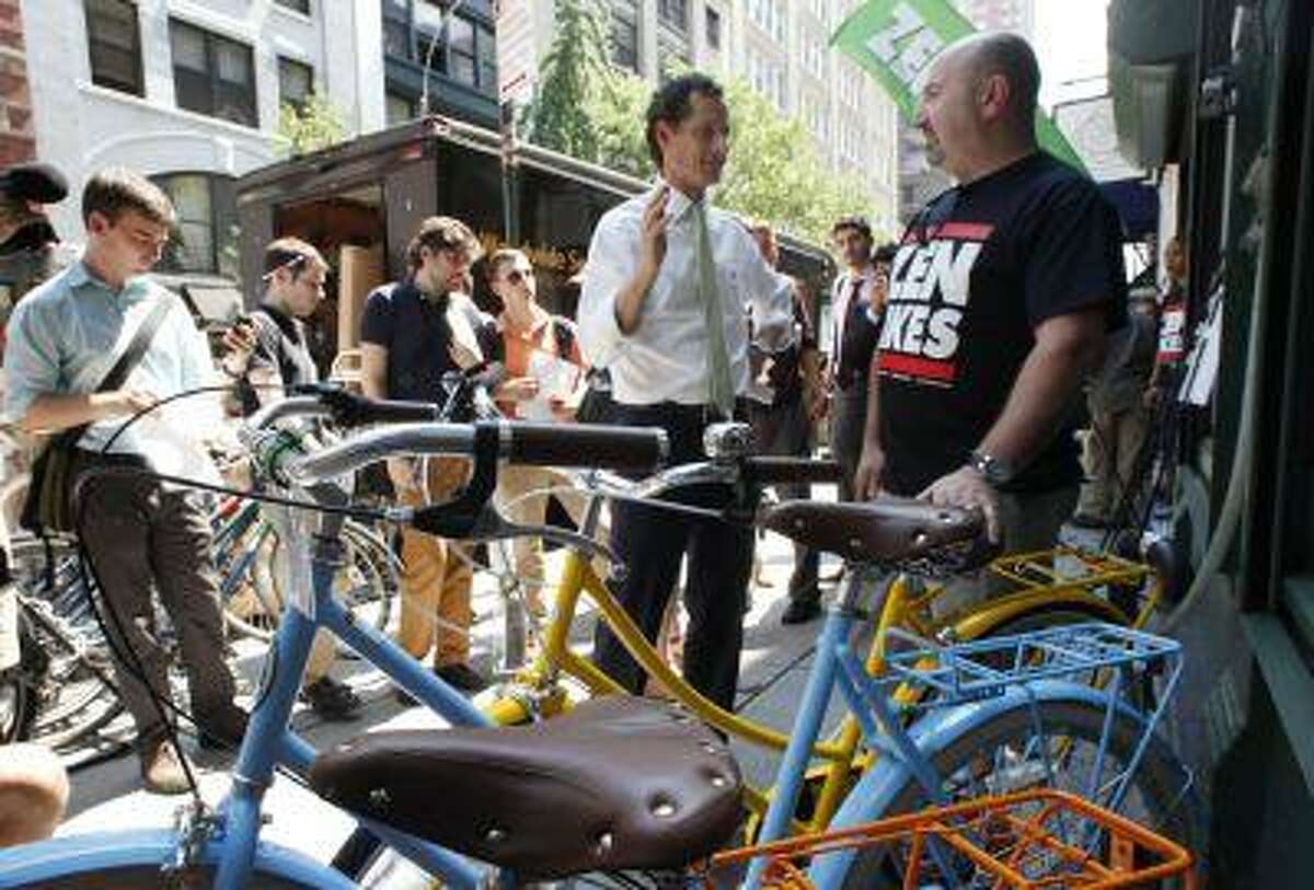 New York mayoral candidate Anthony Weiner, center, meets with John Keoshgerian, right, owner of Zen Bikes, in New York, Monday, July 8, 2013. Weiner is supporting a tax break for employers to encourage employees to bike to work. (AP Photo/Mark Lennihan)