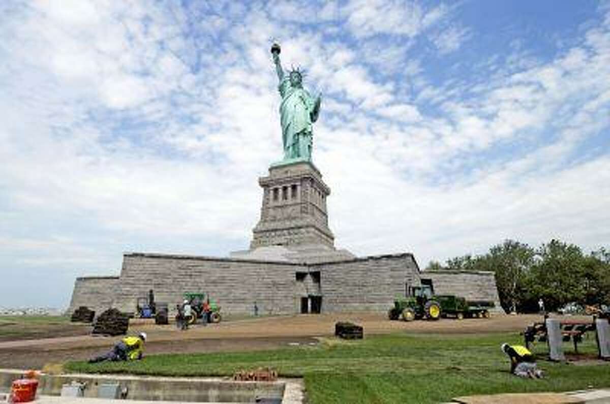 In this June 26, 2013 photo provided by the National Park Service, workers on Liberty Island install sod around the national monument which is set to re-open on the 4th of July, in New York. Months after railings broke, docks and paving stones were torn up and buildings were flooded by Superstorm Sandy, the Statue of Liberty will finally welcome visitors again. (AP Photo/National Park Service)